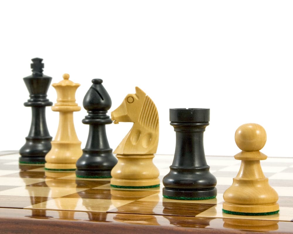 Ebonised Staunton chess pieces on a chessboard, featuring a 3.25 inch king, crafted from boxwood, with an ideal fit for a 17 inch board.