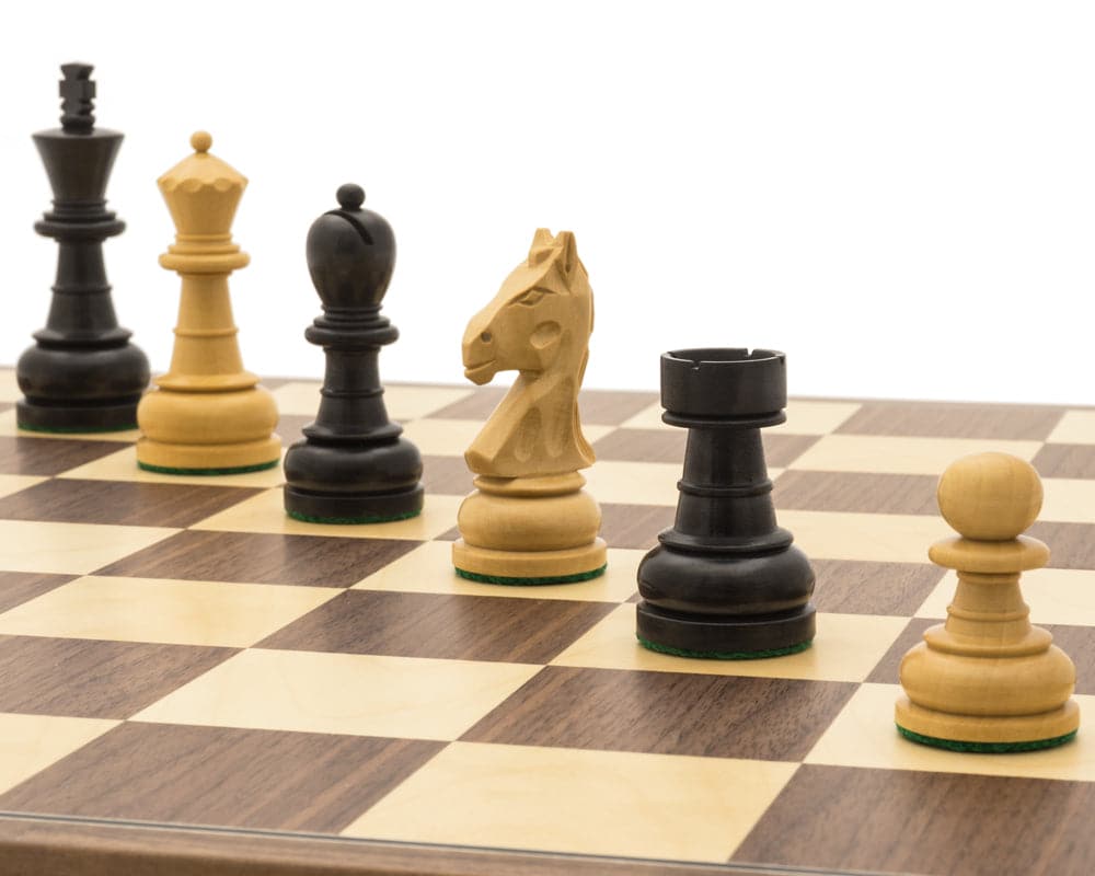 Close-up view of The Emerald Black and Walnut Folding Chess Set pieces on a chessboard