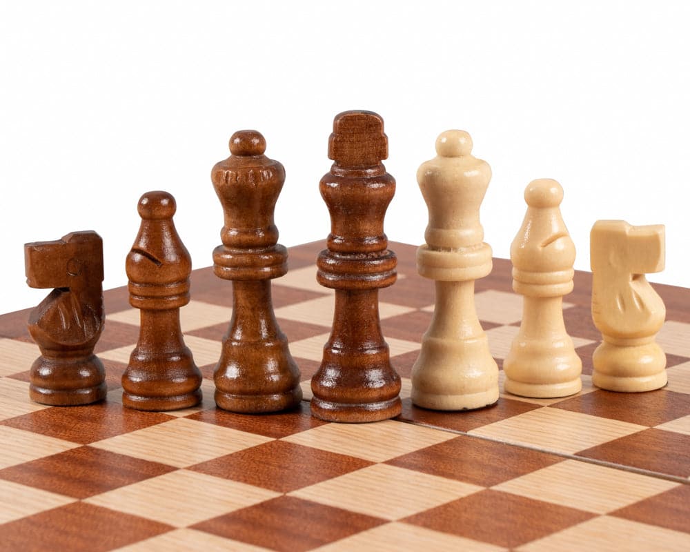 Mahogany and ivory chess pieces on a checkerboard patterned travel-sized chess set.