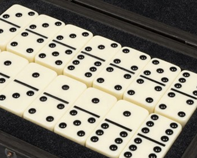 Open case displaying a neatly arranged set of ivory-colored dominoes with black pips.